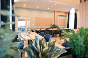 a restaurant with tables and chairs and potted plants at Hotel Merlot in Eger