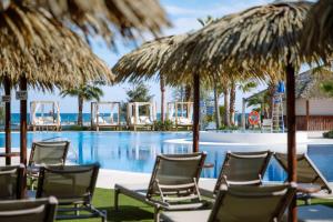 a group of chairs and umbrellas next to a swimming pool at Hotel Tahití Playa & Suites 4Sup in Santa Susanna