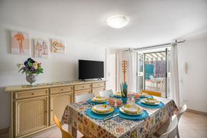 une salle à manger avec une table avec des chaises et une télévision dans l'établissement 2 Terraces and Pergola House in Ischia, à Ischia