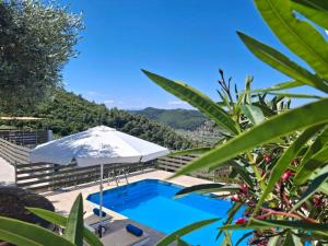 una piscina con una sombrilla blanca en Skopelos villa Konstans, en Skopelos Town