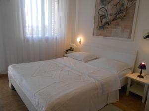 - un lit blanc dans une chambre avec une photo sur le mur dans l'établissement Apartment Studio Antonia, à Medulin