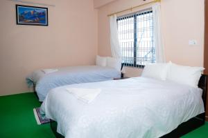 a bedroom with two beds and a window at Misha's Peaceful Retreat Near Pokhara, Free Yoga, cafe, Nature and Comfort in Pokhara