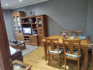 a living room with a table and chairs and a television at El encanto del Texu in Pola de Lena