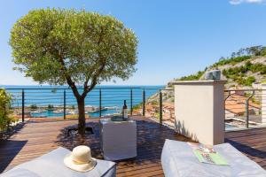 a patio with a tree and a view of the ocean at Portopiccolo Apartments - Ulivo sul golfo in Portopiccolo Sistiana
