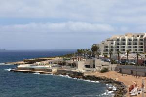 a building on a beach next to the ocean at Seafront living with private Garage in St. Paul's Bay