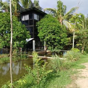 a building with a pond in front of it at Farmsamsook in Ban Pratu Pa Luang