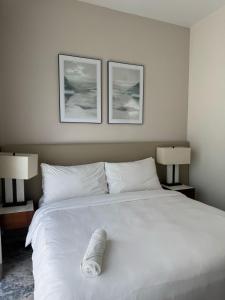a large white bed with two pictures on the wall at Address Beach Resort Fujairah Apartment Three Bedrooms by Blue World- 3 in Fujairah