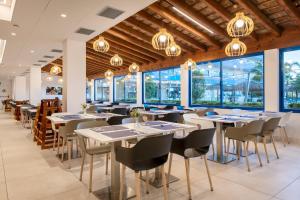 a restaurant with tables and chairs and windows at Hotel Tahití Playa & Suites 4Sup in Santa Susanna