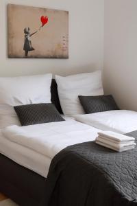 two beds with white sheets and a girl with a heart balloon at AMA Home AMALI - Geräumiges Apartment mit Balkon & Parkplatz - Perfekt für Business & Erholung in Hiddenhausen