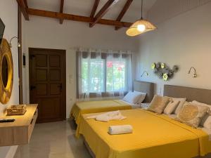 a bedroom with two beds with yellow sheets at Maniatis Garden in Achladies