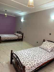 two beds in a room with purple and white walls at Spacieux Appartement Selouane Nador in Selouane +13 photos