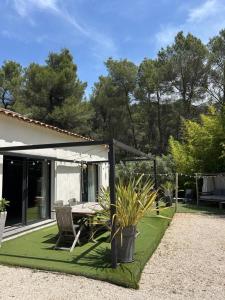 a patio with a table and chairs on a green lawn at Superbe maison avec jacuzzi in Ventabren