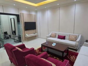 a living room with a couch and chairs and a tv at شقق الشريفة in Al Madinah