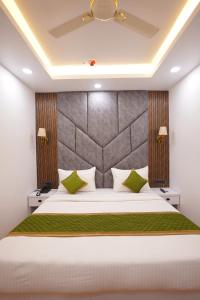 ein Schlafzimmer mit einem großen weißen Bett und grünen Kissen in der Unterkunft Sara Fortune International in Noida