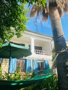 a man sitting in a hammock in front of a house at Apartment in Villa under Grand Palm Tree & Garden in Porto Alabe