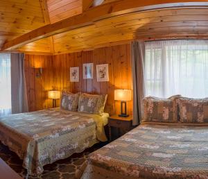 a bedroom with two beds in a room with wooden walls at Hinckleys Dreamwood Cottages in Bar Harbor +250 photos