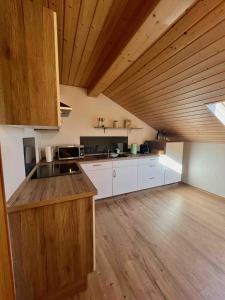 Il comprend une grande cuisine avec des placards blancs et des plafonds en bois. dans l'établissement Home Sweet Home - Gemütliche Ferienwohnung, à Soyen