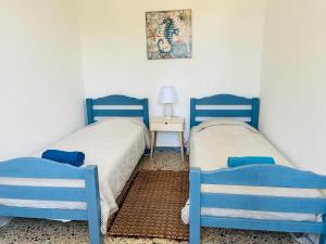 two blue beds in a room with a table and a picture at Apartment in Villa under Grand Palm Tree & Garden in Porto Alabe