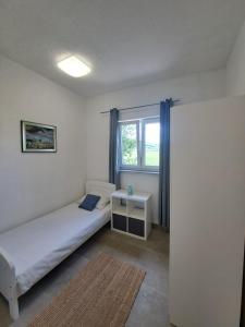 a small bedroom with a bed and a window at Apartman Mia in Perušić