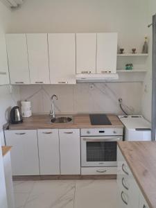 a white kitchen with white cabinets and a sink at Apartman Mia in Perušić +10 photos