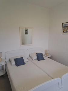 two beds with blue pillows in a white room at Apartman Mia in Perušić