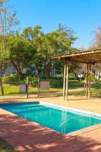 a swimming pool in a yard with a pergola at Golf Estate Living 1BR Apartment in Jackal Creek in Roodepoort
