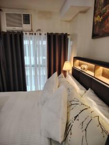 a bedroom with a bed with white sheets and a window at Stylish New Studio at McKinley Hill BGC Free Netflix in Manila