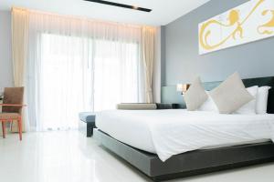a bedroom with a large white bed and a window at Beachfront 1 BR Hotel Infinity Pool Patong Phuket in Patong Beach