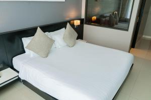 a bed with white sheets and pillows in a room at Beachfront 1 BR Hotel Infinity Pool Patong Phuket in Patong Beach