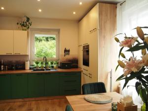 a kitchen with green cabinets and a table and a window at ZIELONO Mi 2 in Jedlina-Zdrój