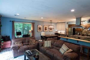 a living room with two brown couches and a kitchen at Spacious Catskills Home with Covered Hot Tub in Monticello