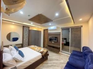 a bedroom with a bed and a couch and a tv at Multazam Heights, DHA Phase 8, Hotel Airport Lahore in Lahore