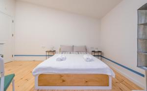a bedroom with a bed with white sheets and wooden floors at orbeliani blue line in Tbilisi City