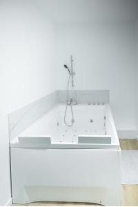 a white bathroom with a tub with a shower at Sémillon - Baignoire Balnéo plein centre in Bergerac