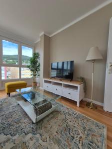 a living room with a tv and a glass table at Chelsea Cedeira VIVIENDAS USO TURISTICO in Cedeira