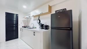 a kitchen with a black refrigerator and white cabinets at 2 Beds Spacious Centrally Located Loft Apartment in Naga +17 photos