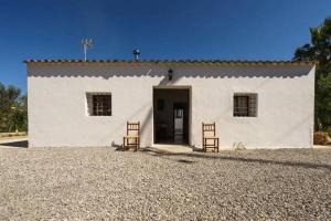 a white building with two chairs in front of it at Can Beia Rural House Ibiza in Nuestra Señora de Jesus
