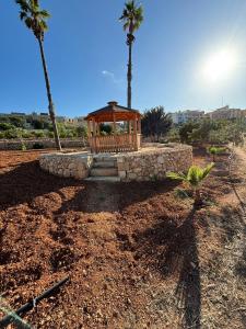 a gazebo in a field with two palm trees at Hal Wardija Resort Apartments in Qala