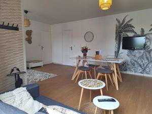 a living room with a table and chairs and a tv at Chez Léonie in Sainte-Mère-Église