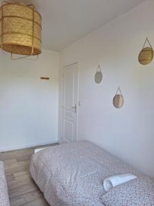 a white bedroom with a bed and a lamp at Chez Léonie in Sainte-Mère-Église