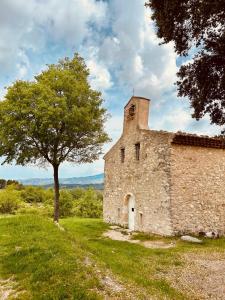 an old stone building with a tree next to it at La Sarrasine in Villes-sur-Auzon