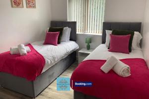 two beds in a bedroom with red and white pillows at Convenient 2-bedroom Second Floor Flat By Escape & Estates Short Lets & Serviced Accommodation Oldbury with Free Parking in Oldbury