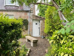 a bench in front of a building with a white door at Craigen Cottage Ballater in Ballater