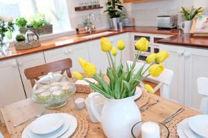 a kitchen table with yellow tulips in a white vase at Craigen Cottage Ballater in Ballater