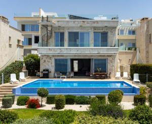 a villa with a swimming pool in front of a house at Olymp Luxury Villa D - Luxury Escape with Direct Beach Access and Unique Sunsets in Paphos +73 photos