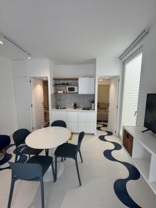 Una habitación con una mesa y sillas y una cocina. en Soleonde, en Marina di Ragusa