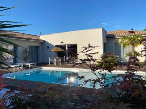 a villa with a swimming pool in front of a house at La Musardise Guest House in Berson
