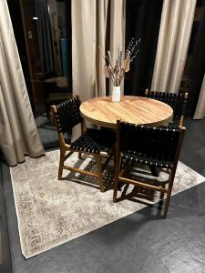 a wooden table with two chairs and a vase with flowers at Brown Deer - z Sauną na Tarasie, Jacuzzi i Widokiem na Góry - by Deer Hills Luxury Apartments in Kocoń