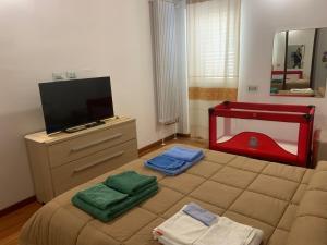 a bedroom with a bed with two towels and a tv at PiazzaItaliaSuite appartamento con terrazza in Cagliari