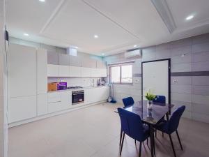 a kitchen with a dining table and blue chairs at Kings View Apartment in Achimota